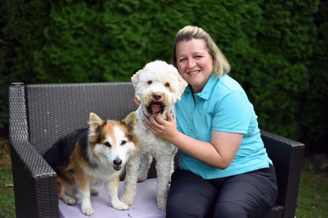 Mobile Physiotherapie für Hunde: Tierphysiotherapeutin im entspannten Umgang mit einem Lagotto Romagnolo und einem Mischling im Freien.